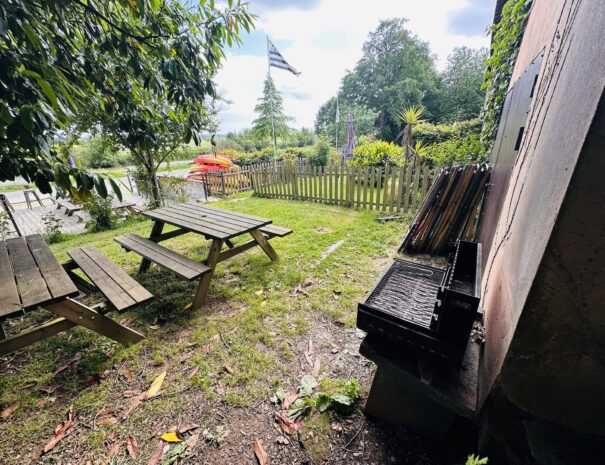 Barbecue et tables de jardin à côté de la terrasse